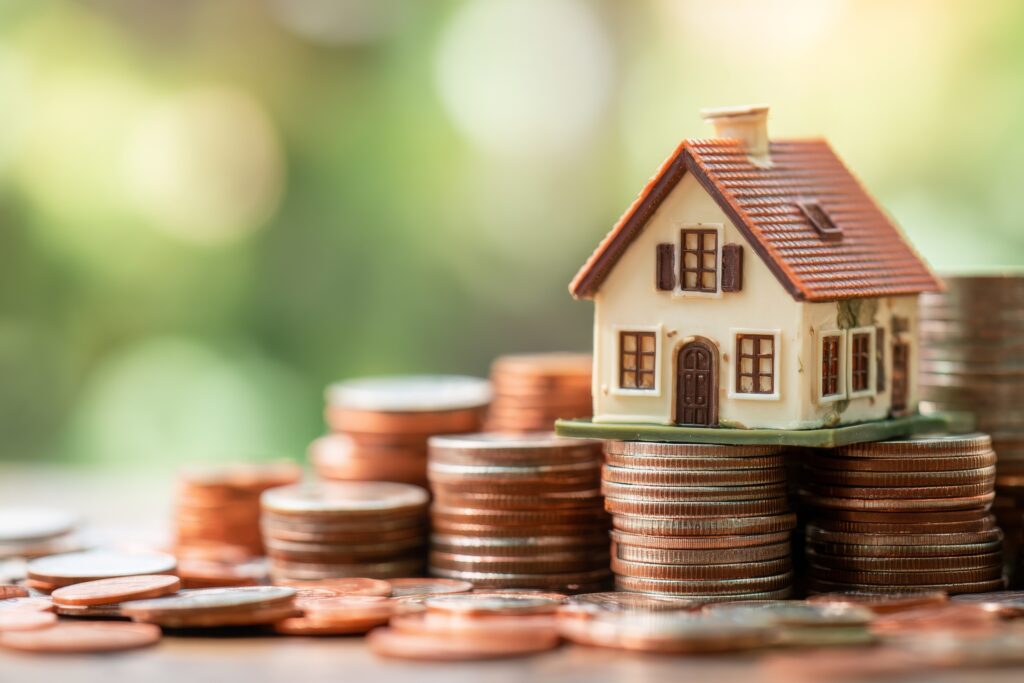 Mortgage loan or home equity loan, financial concept : Tiny model residential house perched atop coin stacks, depicting home loan or borrowing money to purchase a new home for first time homebuyer.