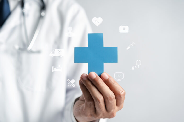 Medical professional holding a blue cross card with floating healthcare icons around it, conveying health services.