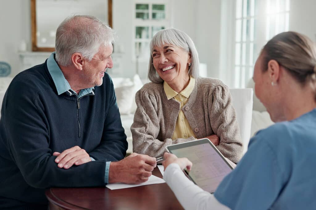 Happy, old couple and caregiver in home with tablet, form and report for medical results. Nurse, senior people or checkup in living room with digital, application and information for health insurance.